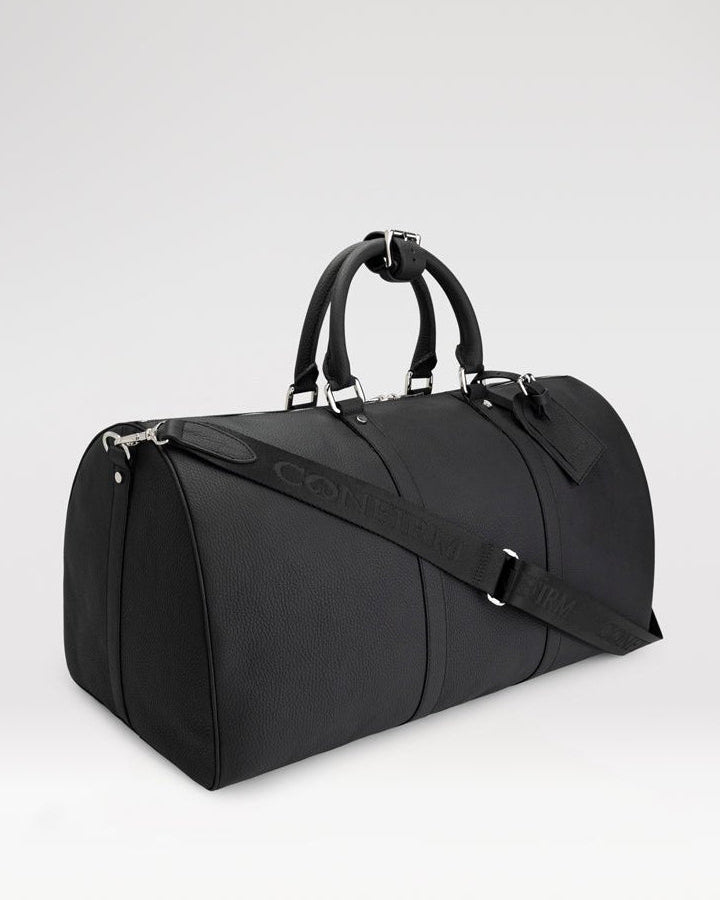 Confirm 55-inch leather travel bag with spade details, travel tag, hand handles, and detachable shoulder strap.