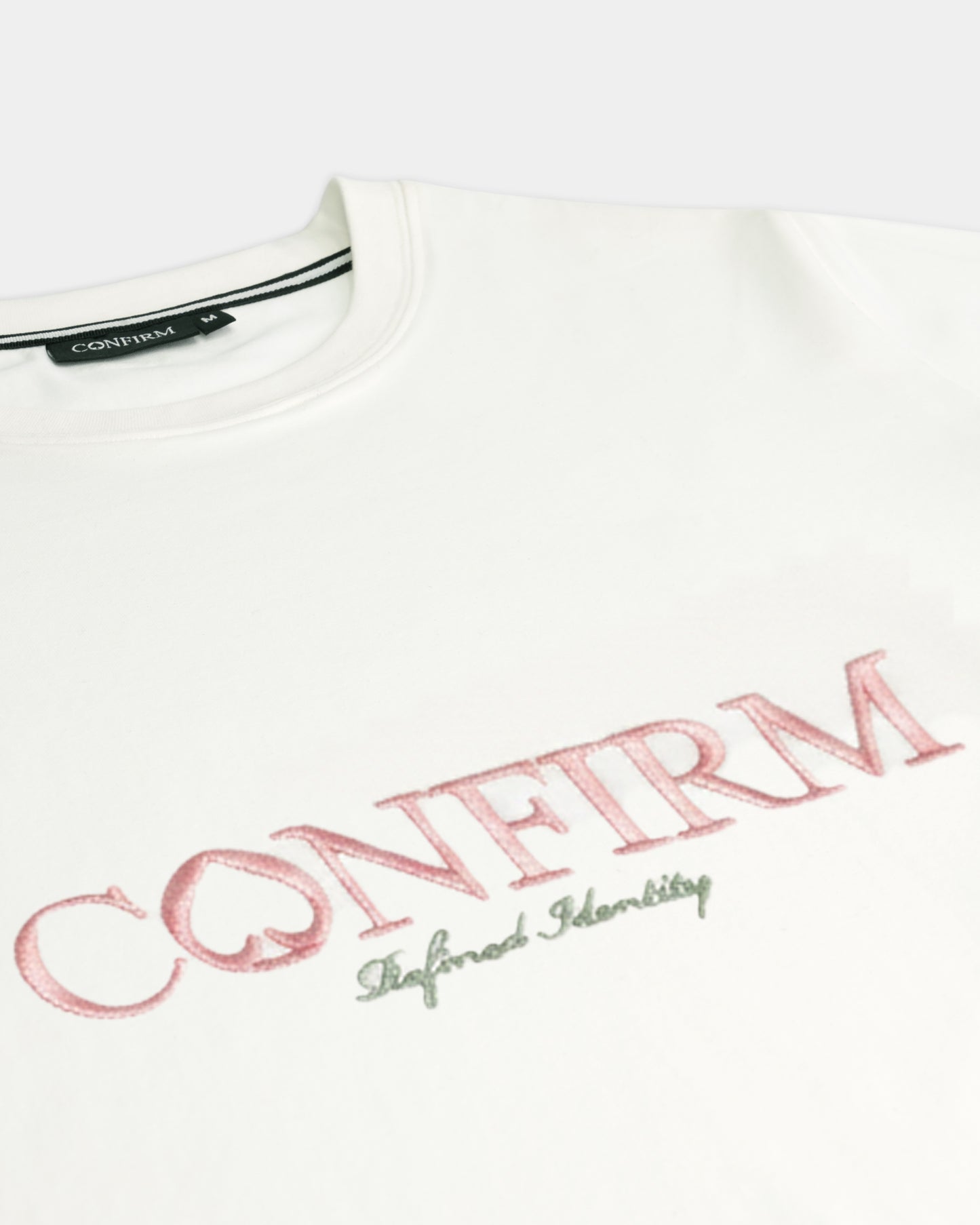 Close-up van de luxe CONFIRM-borduring op het Refined Identity T-shirt in off-white